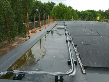 Solar panels installed beside a rainwater-covered flat roof