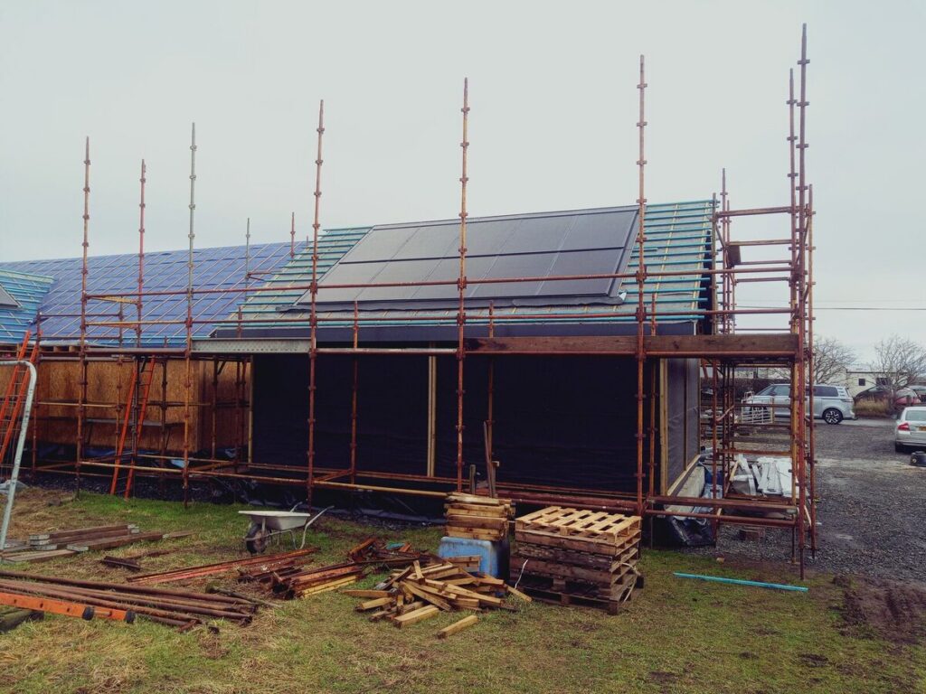 Solar panels being installed on scaffolded house roof