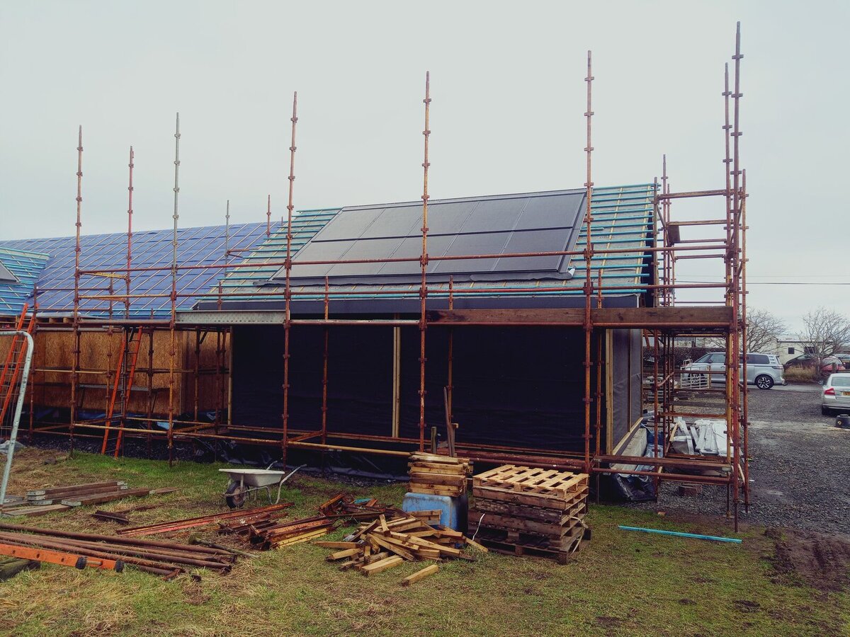 Solar panels being installed on scaffolded house roof
